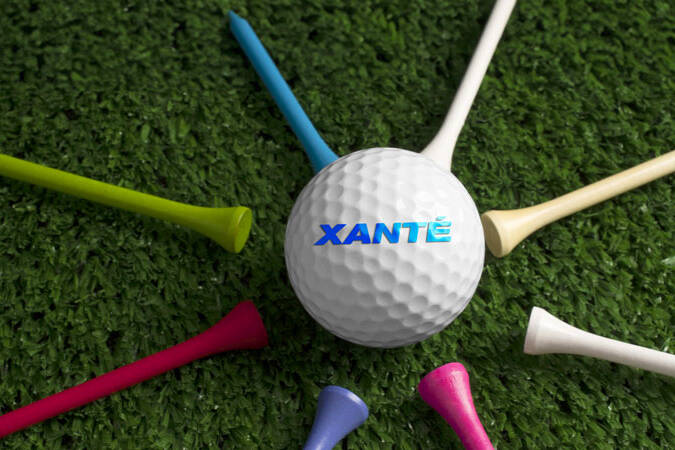 Printed Xante logo on white golf ball surrounded by colorful tees